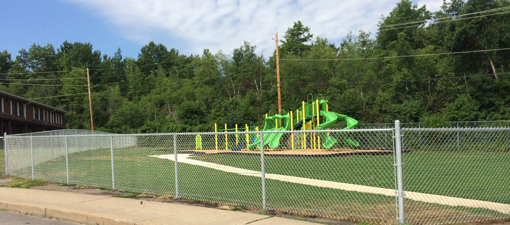 Chain-link fence enclosure around a community playground providing safe boundaries for children